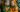 Zwei Kinder in Kürbiskostümen sitzen vor Kürbissen